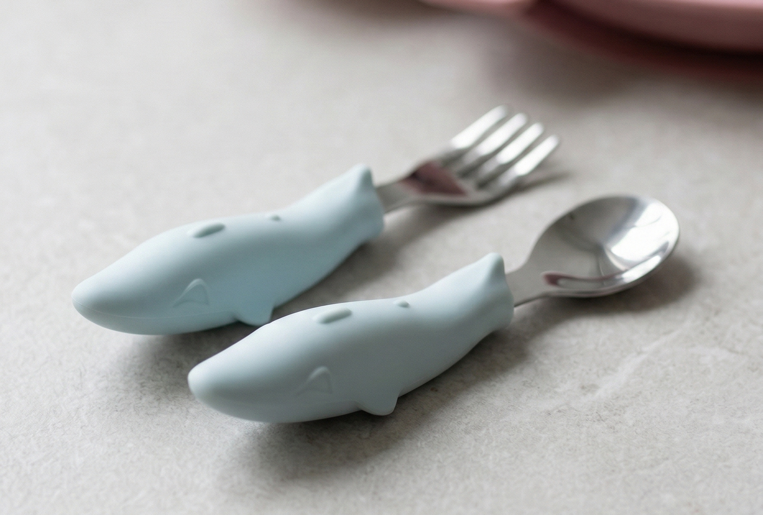 Children's cutlery set with whale handles on a neutral background.